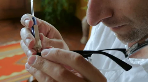 Man repairs glasses with tiny screwdriver - handheld Stock Footage 65338805