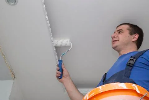 Man repairs the house inside with roller and bucket Stock Photos