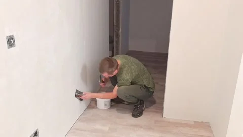 Man repairs wall in indoor space during home renovation process Stock Footage 326698348
