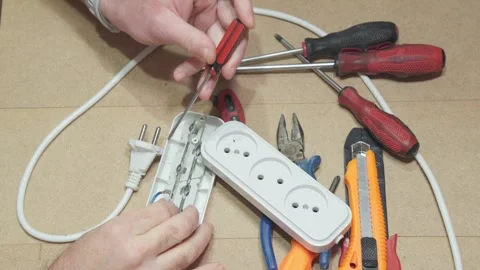 A man repairs a white electrical socket extension cord surrounded by hand t.. Stock Footage 288979328
