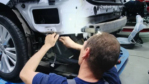 Man repairs wires on back of car sitting near wheel Stock Footage 317634112