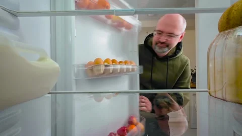 Man repeatedly opening fridge and looking inside with hopeful expression, view Stock Footage 314101984