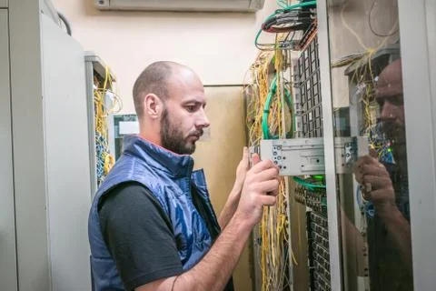 The man replaces the server in the rack. The engineer removes computer equipm 库存照片