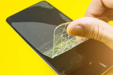 Man replacing the broken tempered glass screen protector. Crashed smartphon.. Stock Photos