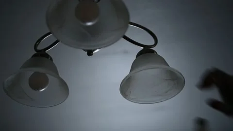 A man replacing his dining room light bulb Stock Footage 146143432