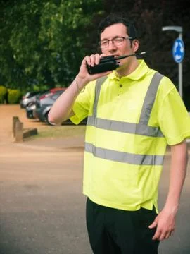 Man reporting a message through walkie talkie in high viz jacket Stock Photos