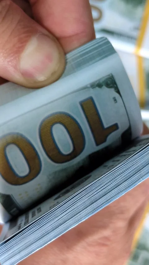 A man is rereading a stack of hundred dollar bills Stock Footage 314381513