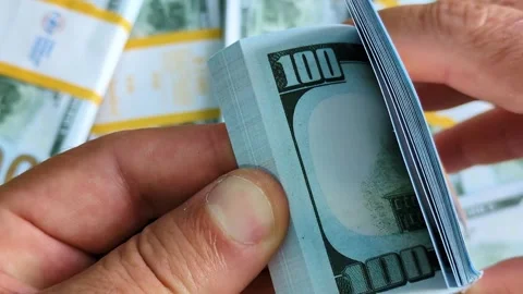 A man is rereading a stack of hundred dollar bills Stock Footage 314381545