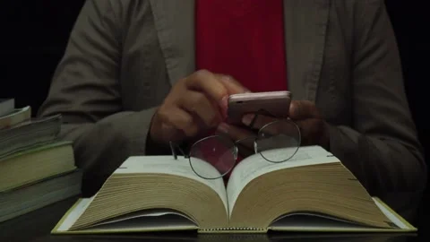 Man researching both smartphone and book at night. Stock Footage 182472293