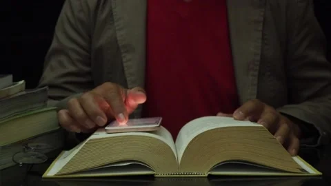 Man researching both smartphone and book at night. Stock Footage 182472801