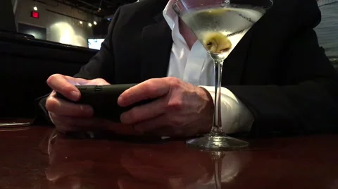 Man in a restaurant texting on his smart phone and drinking a martini Stock Footage 62482156