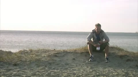 A man resting after jogging on the beach Stock Footage 11287072