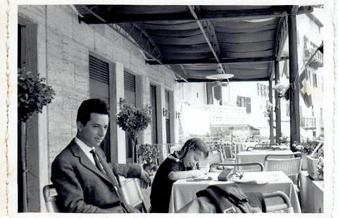 A man resting after lunch while his daughter is drawing next to him (1960) Stock Photos