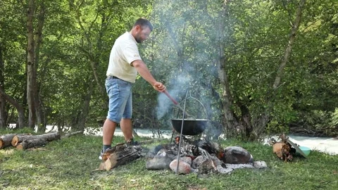 Man resting and cooking in pot on fire. Tourist trip. Camping. Summer outdoor Stock Footage 266160559
