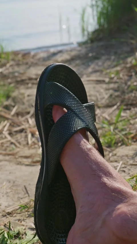 Man Resting Bare Foot in Black Sandal on Sandy River Shoreline Stock Footage 342185059