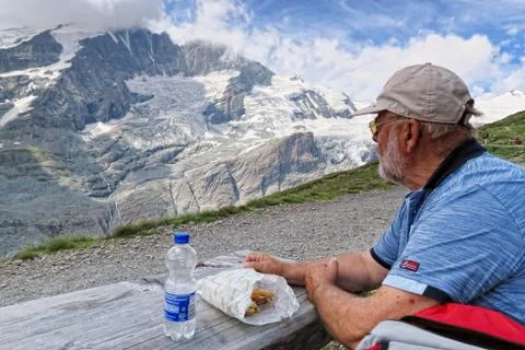 Man resting on a beach and eating breakfast. hiking in grossglockner mountain Stock Photos