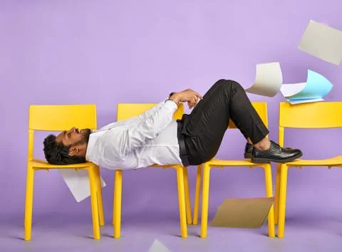 Man resting on chairs throwing up documents Stock Photos