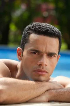Man resting chin on hands, side of pool Stock Photos