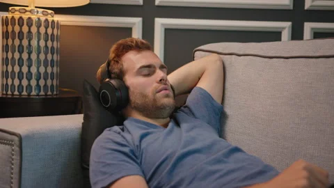 Man resting at couch with big headphone on Stock Footage 130297763