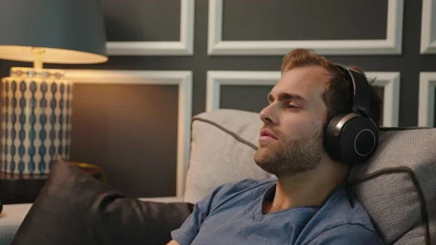 Man resting at couch with big headphone on Stock Footage 130297767