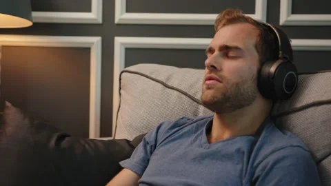 Man resting at couch with big headphone on Stock Footage 130297794