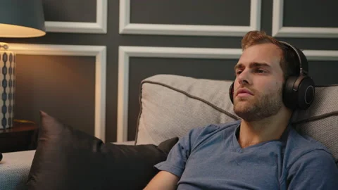 Man resting at couch with big headphone on Stock Footage 130297799
