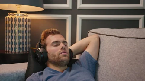 Man resting at couch with big headphone on Stock Footage 130297801