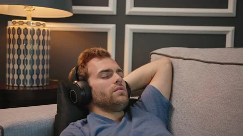 Man resting at couch with big headphone on Stock Footage 130297813