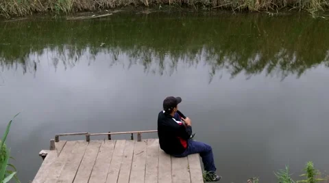 Man is resting on the dock by the river Stock Footage 50367807