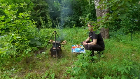 Man resting on folding chair while cooking food in campfire cauldron outdoo.. Stock Footage 344869240