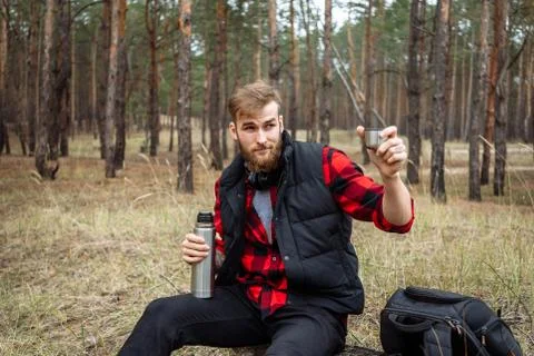 Man resting in the forest and drinking tea from the thermos Stock Photos