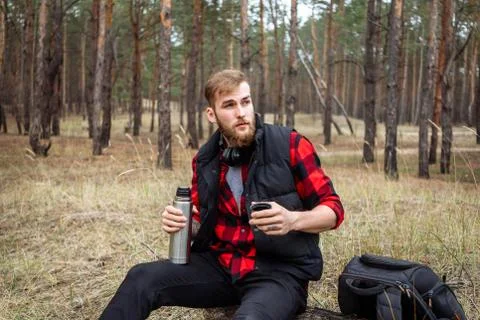 Man resting in the forest and drinking tea from the thermos Stock Photos