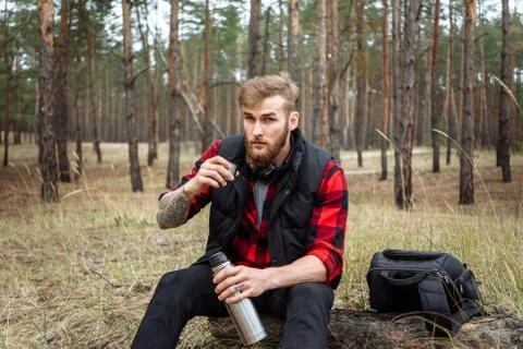Man resting in the forest and drinking tea from the thermos Stock Photos
