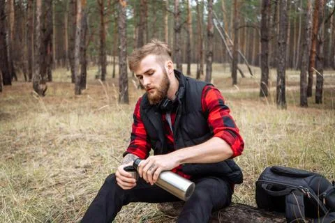 Man resting in the forest and drinking tea from the thermos Stock Photos