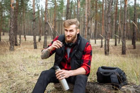 Man resting in the forest and drinking tea from the thermos Stock Photos