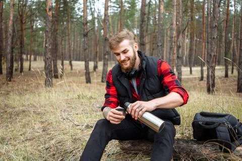 Man resting in the forest and drinking tea from the thermos Stock Photos