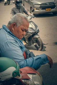 Man resting head on arms while sitting on a red scooter on Foto stock