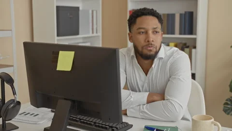Man resting head on folded arms at office desk with computer monitor, noteb.. 動画素材 337439889