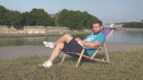 Man is resting, lying on sunbed by the river. 库存影片 65205658