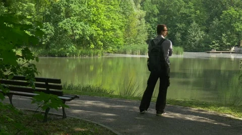 Man Resting in Park Standing at the Bench by Lake Tourist in Park Fresh Green Stock Footage 63809967