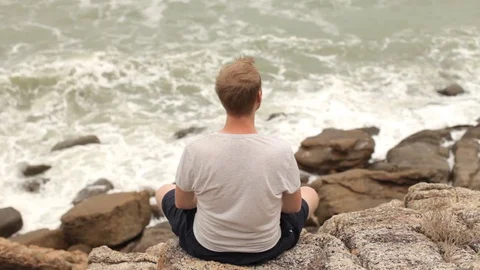 Man is resting on the rocks on the seashore Stock Footage 85932536