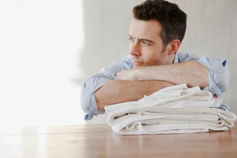 A man resting on a stack of folded laundry, day dreaming 스톡 사진