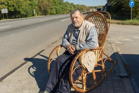 Man resting while sitting in a wicker rocking-chair at roads Foto stock