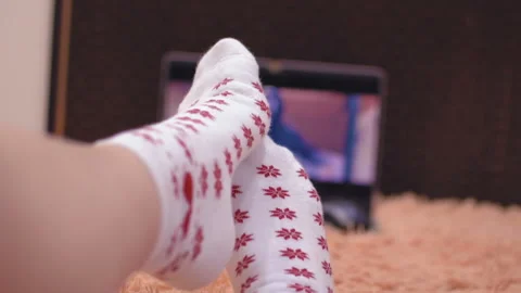 A man is resting while watching a movie. Warm white socks on your feet. Stockbeeldmateriaal 100822857