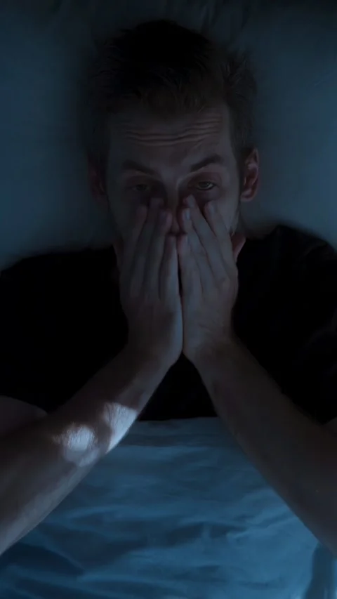 Man restlessly sleeping in bed at night and waking up abruptly with a startle Stock Footage 314023587