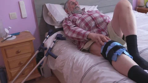 Man rests on bed, adjusting knee brace Stock-Footage 335280227