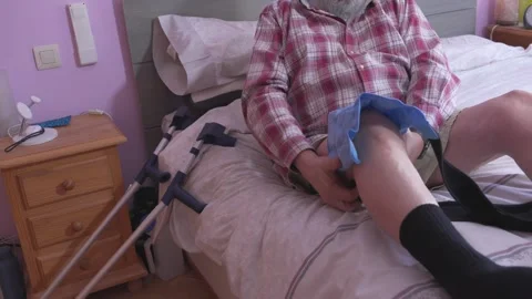 Man rests on bed, adjusting leg support Stock Footage 335280201