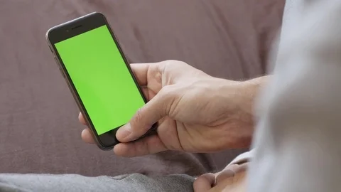 Man rests in bed and looking to greenscreen smart phone Stock Footage 74018444