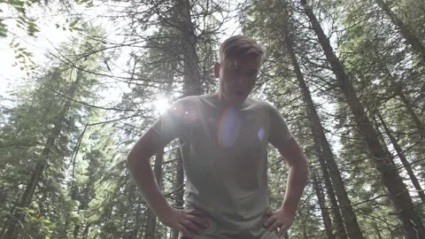 A man rests during a training run in the forest. boy is preparing for a marathon Stock Footage 214326320