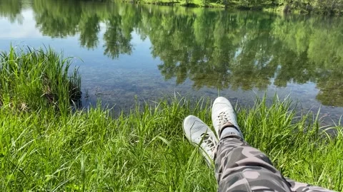 A man rests on the grass by the lake. Video stock 155109748
